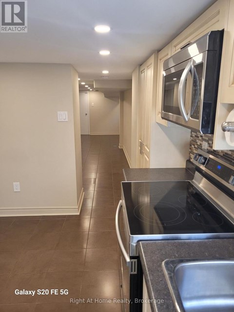 A kitchen with a black counter top and a stainless steel sink.