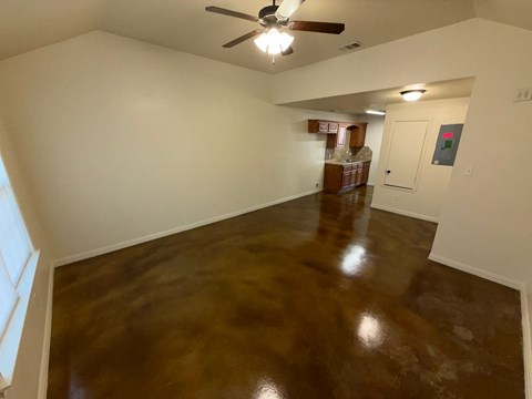 A room with a brown floor and a ceiling fan.