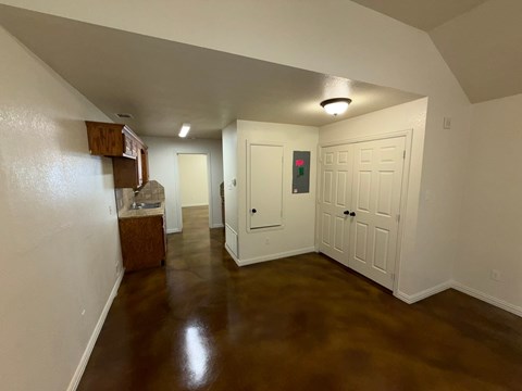 A hallway with a red light on a wall and white doors.