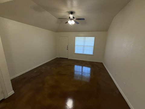 A room with a brown floor and a ceiling fan.