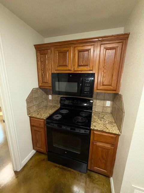 A kitchen with wooden cabinets and black appliances.