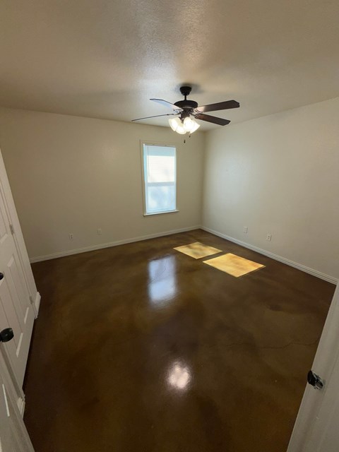 A room with a ceiling fan and a window.