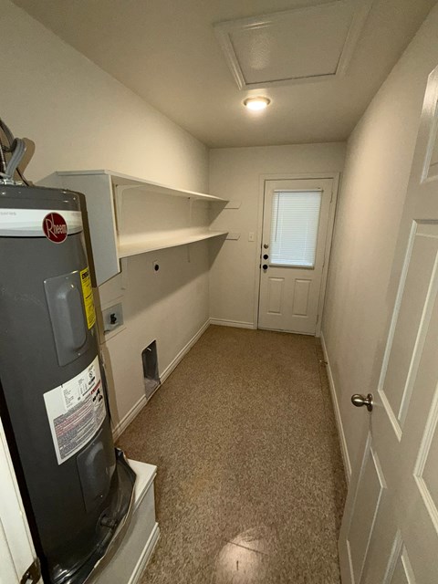 A small room with a fridge and a door.