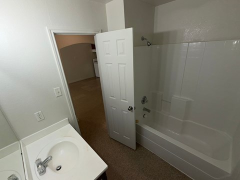 A white bathroom with a sink and a bathtub.