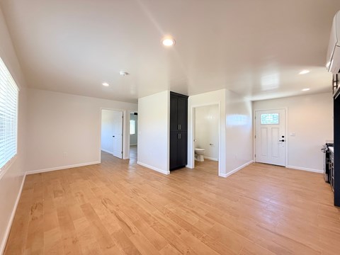 A spacious room with wooden flooring and white walls.