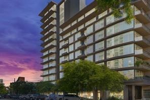 A tall building with balconies and trees in front of it.