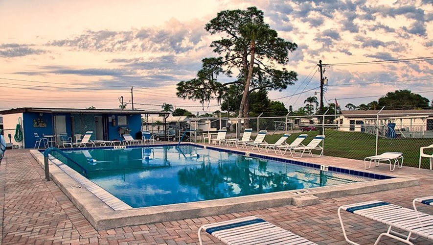 A pool with chairs around it and a building in the background.