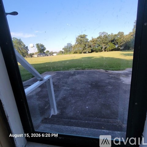 A view from inside a building looking out onto a patio with a water tower and trees in the distance.