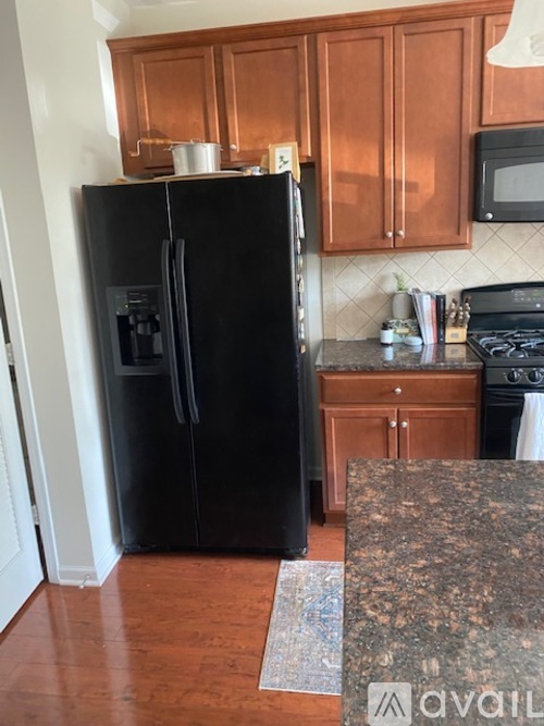 A black refrigerator in a kitchen with wooden cabinets.