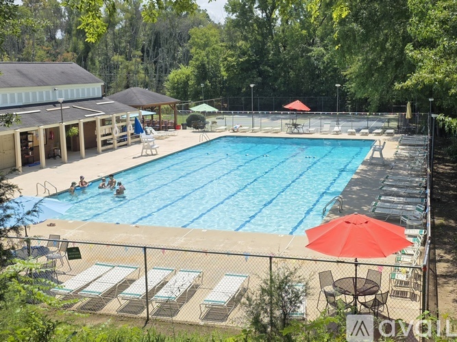 A large outdoor swimming pool surrounded by trees and a fence.
