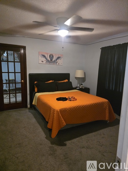A bedroom with a bed, a ceiling fan, and a painting on the wall.