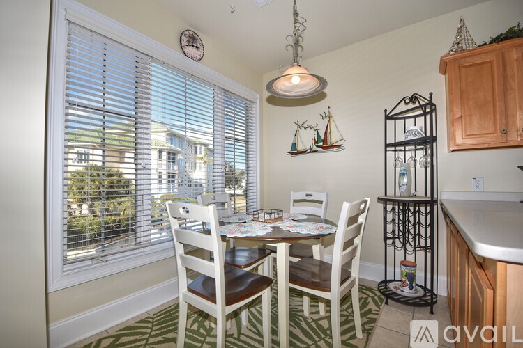 A dining room with a table set for four and a view of the outside through the window.