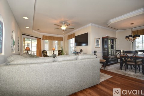 A living room with a grey sofa and a television mounted on the wall.