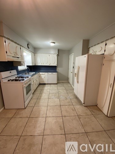 A kitchen with white appliances and tiled floors.