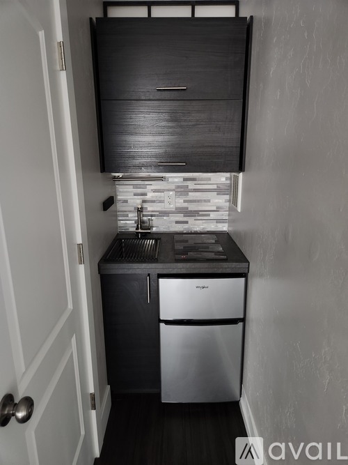 A kitchen with a stainless steel dishwasher and a black cabinet above it.