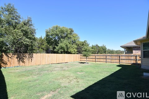 A backyard with a wooden fence and a house in the background.