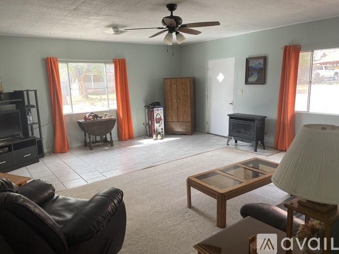 A living room with a black leather chair, a wooden coffee table, and a ceiling fan.