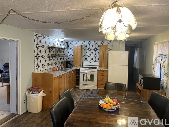 A kitchen with a wooden table and chairs, a white refrigerator, and a chandelier hanging from the ceiling.