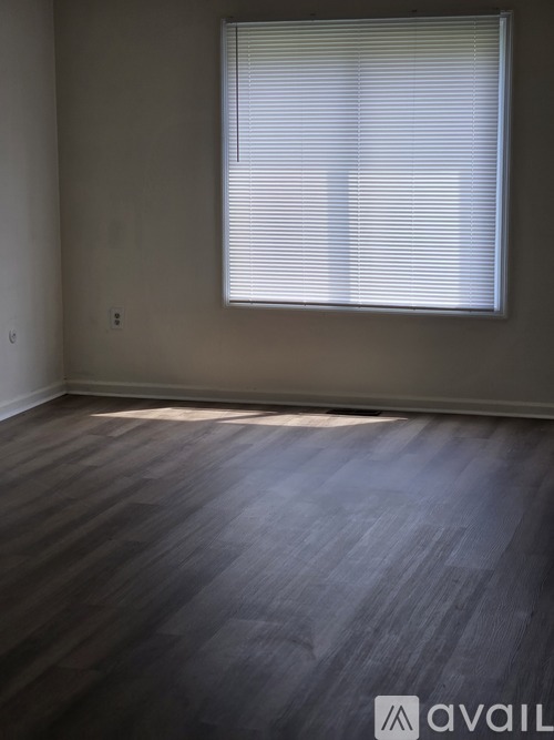 A room with wooden flooring and a window with blinds.