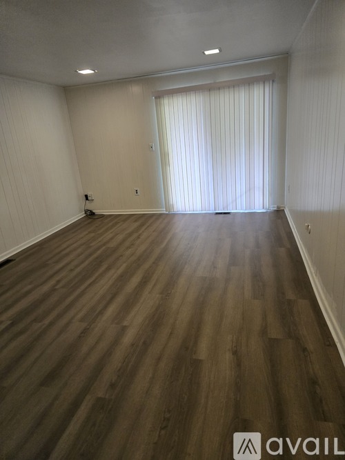 A room with wooden flooring and white walls.