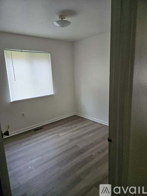 A room with a window and wooden flooring.