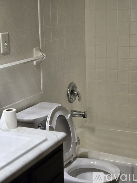 A white toilet with a roll of toilet paper on top of it.