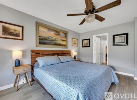 A bedroom with a bed, a ceiling fan, and pictures on the wall.