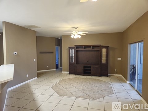 A spacious living room with a television and a rug on the floor.