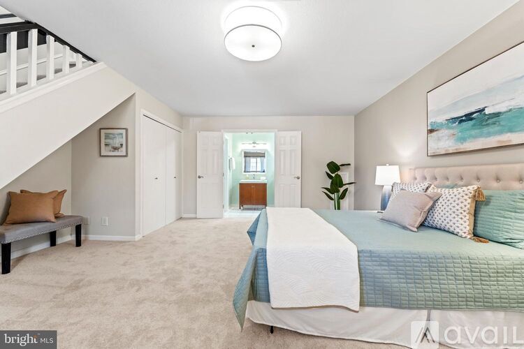 A bedroom with a bed, a bench, and a painting on the wall.