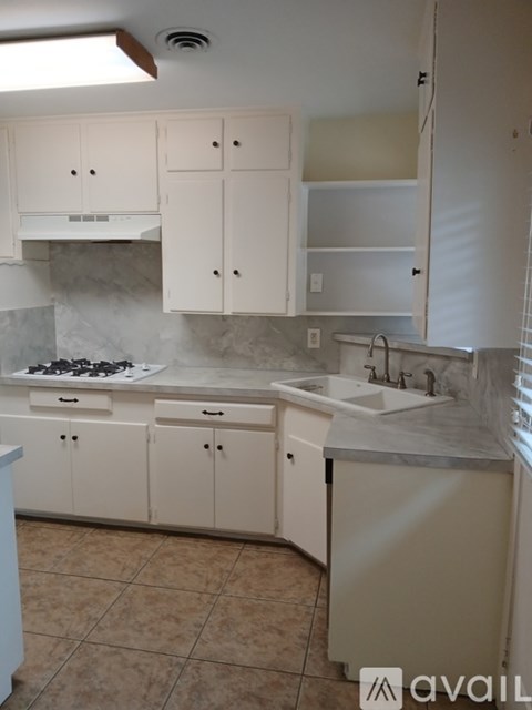 A kitchen with white cabinets and a tiled floor.