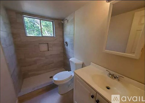 A bathroom with a toilet, sink, and a window.