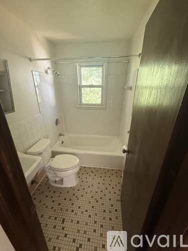 A bathroom with a toilet, tub, and window.