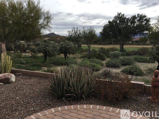 A garden with a circular brick walkway and a variety of plants.