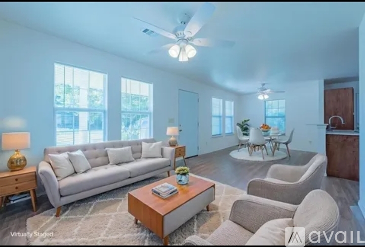 A living room with a white sofa, a wooden coffee table, and a ceiling fan.