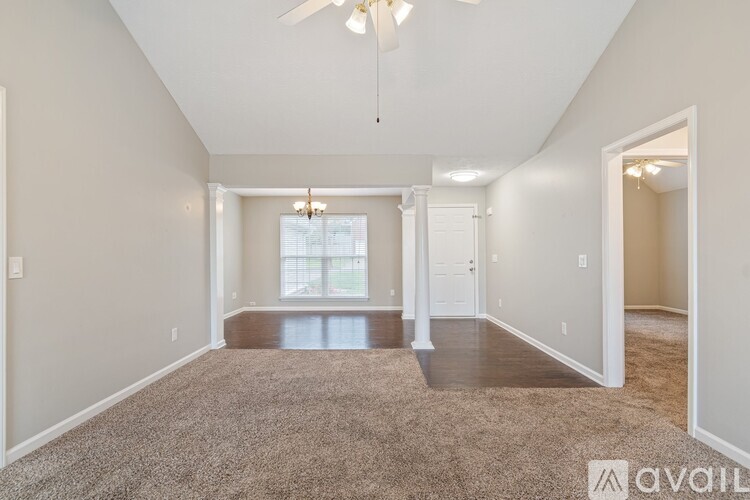 A spacious room with a carpeted floor and a ceiling fan.