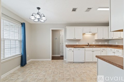 A kitchen with white cabinets and a tile floor.