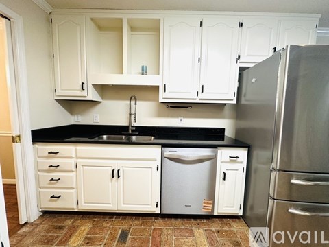 A kitchen with white cabinets and a black countertop.