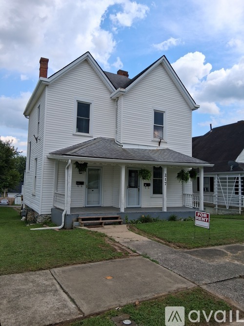 A two-story white house with a porch and a sign in front.