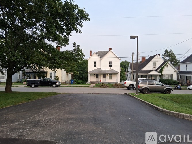 A white house with a garage is situated in a green yard.