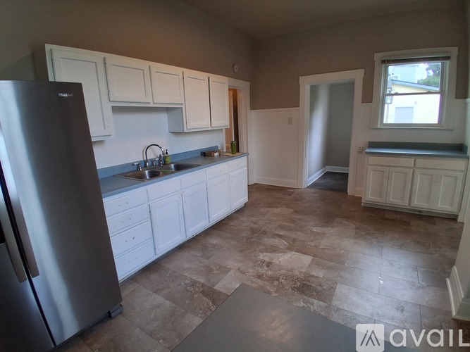 A kitchen with a refrigerator, sink, and cabinets.