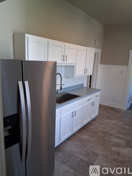 A kitchen with a stainless steel refrigerator and white cabinets.