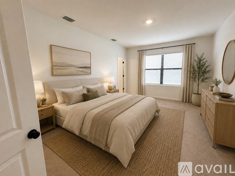 A well-lit bedroom with a large bed, a side table with a lamp, and a painting on the wall.