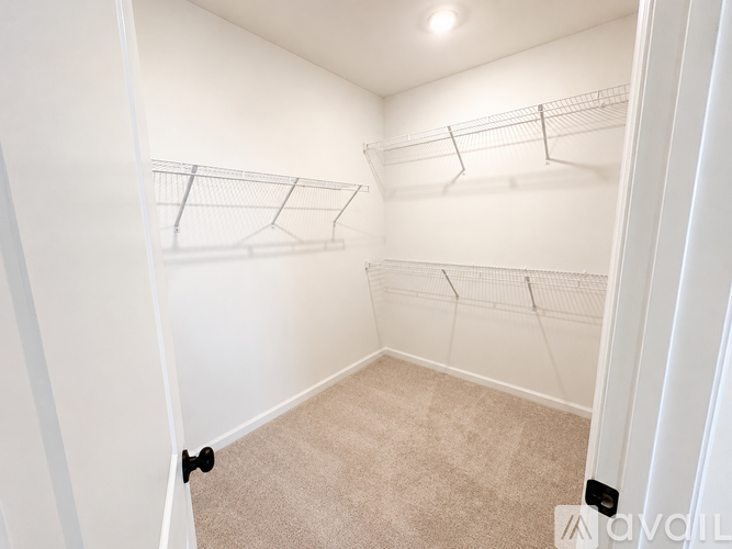 A spacious room with a carpeted floor and a doorway leading to another room.