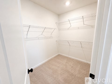 A spacious room with a carpeted floor and a doorway leading to another room.