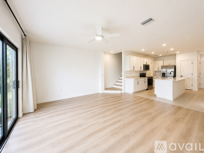 A spacious living room with a ceiling fan and lighting.