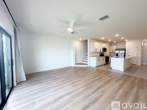A spacious living room with a ceiling fan and lighting.