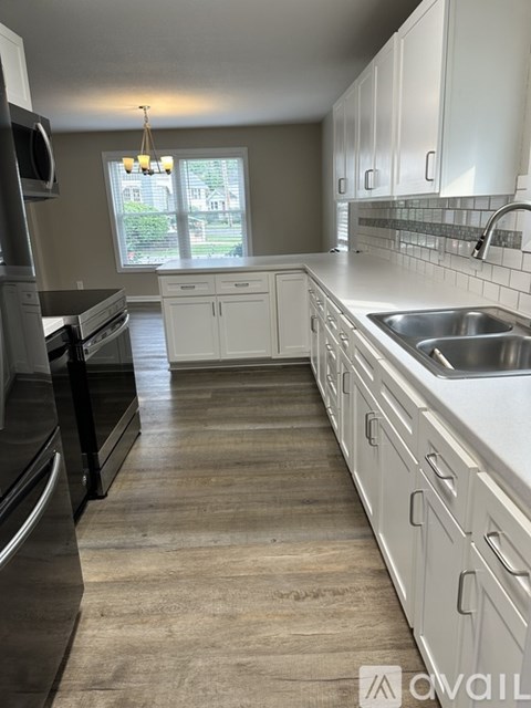 A kitchen with white cabinets and a stainless steel sink.