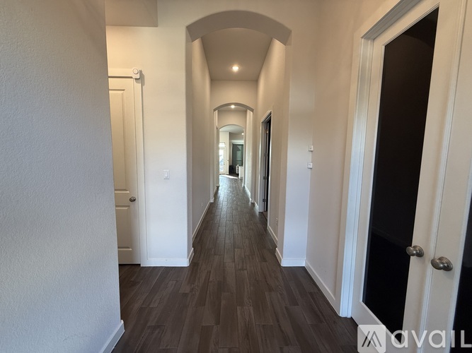 A long hallway with a wooden floor and white walls.