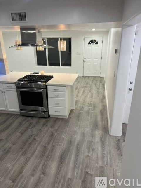 A modern kitchen with a white countertop and a black stove top oven.