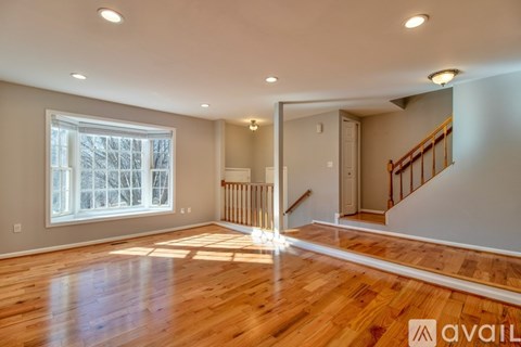 A spacious room with wooden floors and a staircase leading to another room.